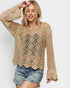 Woman wearing a beige crochet sweater and denim shorts on a white background
