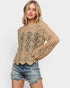 Woman wearing a beige crochet sweater and denim shorts on a white background