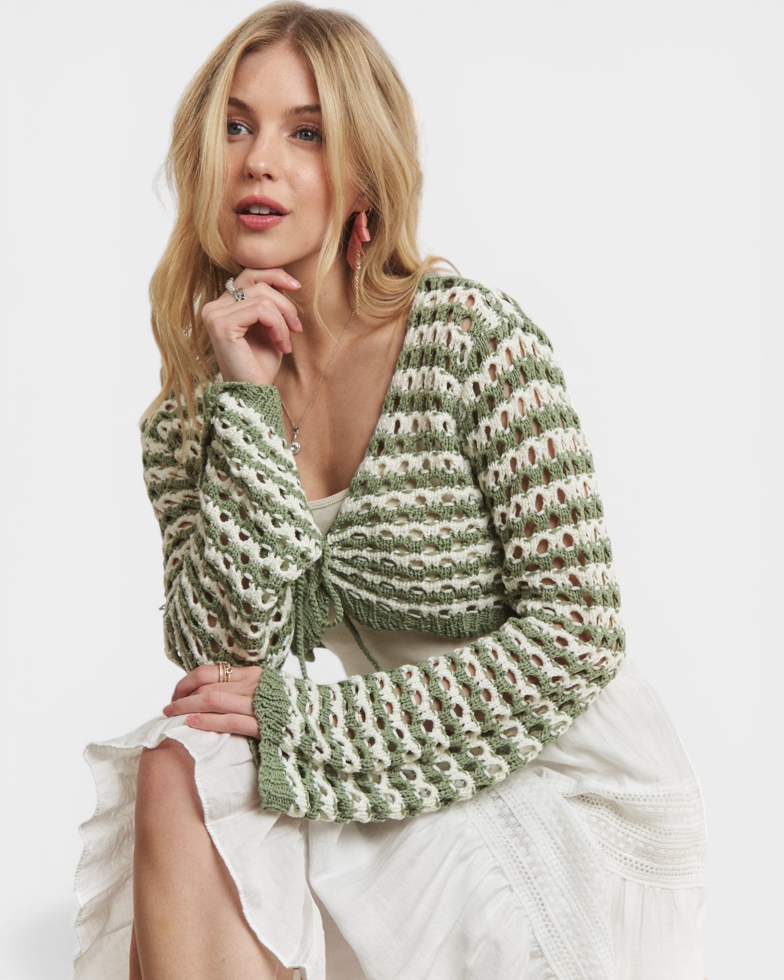 Woman wearing a green and white patterned shrug on a white background