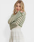Woman wearing a green knitted sweater over a white dress on a white background