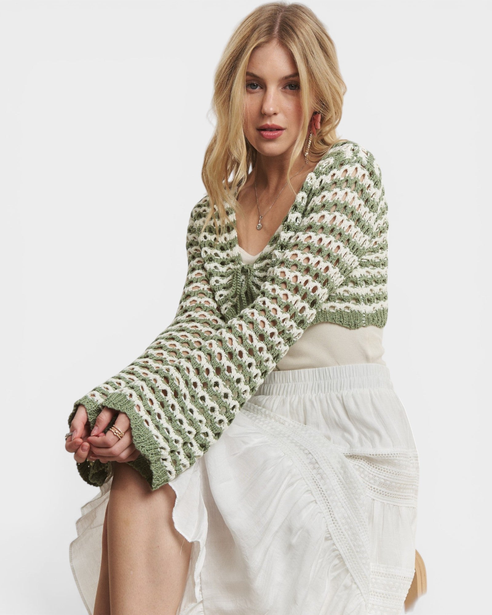 Woman wearing a green and white patterned sweater on a plain background