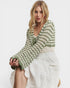 Woman wearing a green and white patterned sweater on a plain background