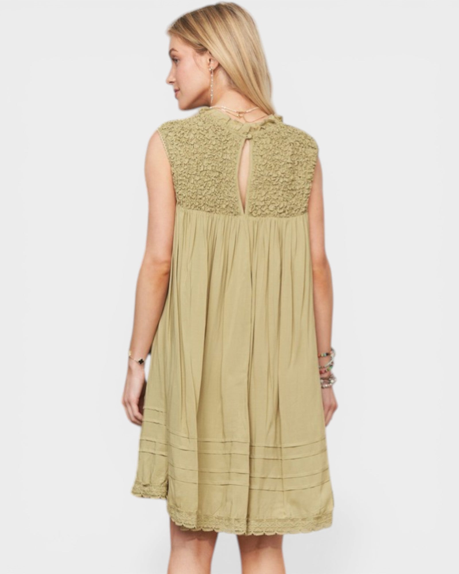 Woman wearing a light green dress with lace details on a white background