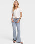 Woman wearing a white blouse and light blue jeans on a plain background