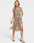 Woman wearing a colorful dress with denim shorts on a white background