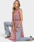 Woman wearing a pink sleeveless top and light blue jeans on a white background