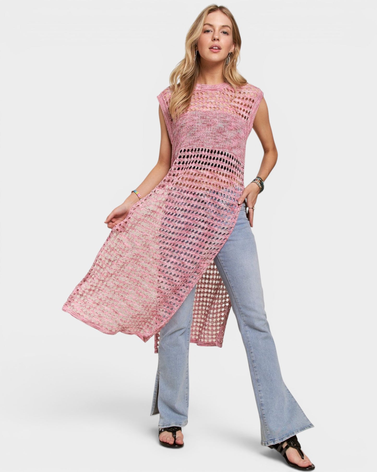 Woman wearing a pink crochet top and blue jeans on a white background
