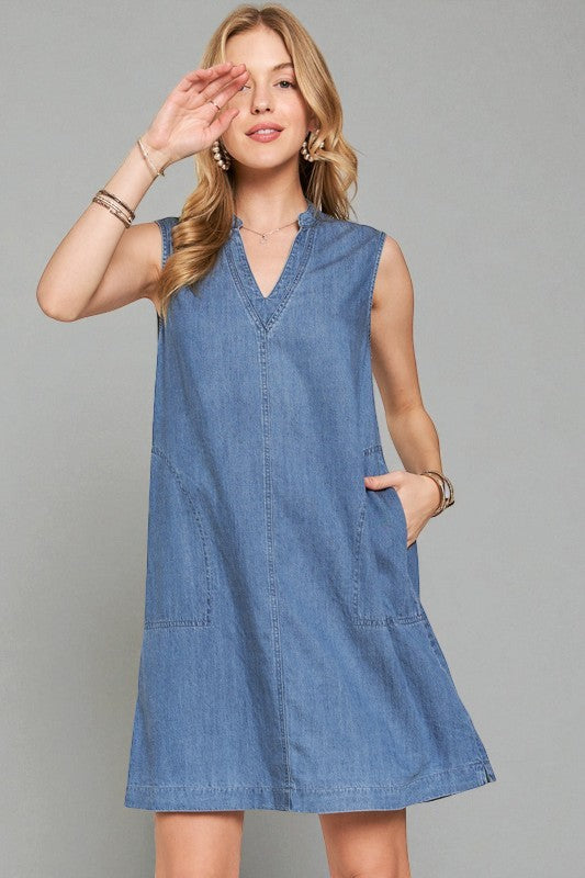 Woman wearing a blue denim dress against a gray background