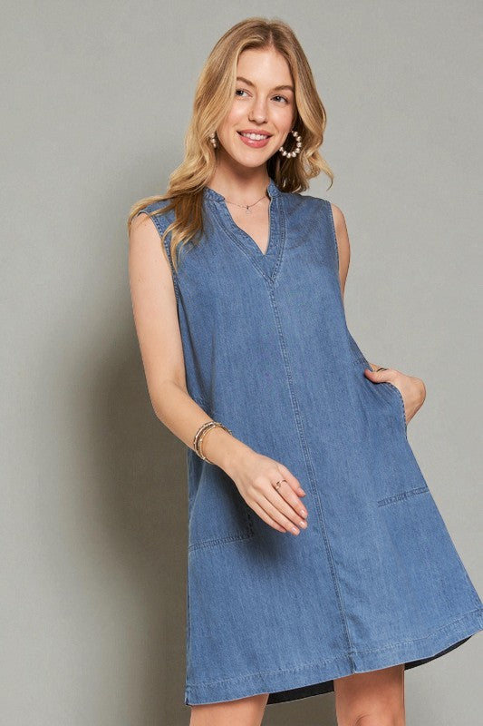 Woman wearing a blue denim dress against a gray background