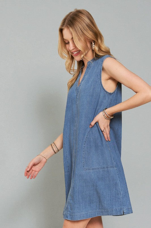 Woman wearing a blue denim dress against a gray background