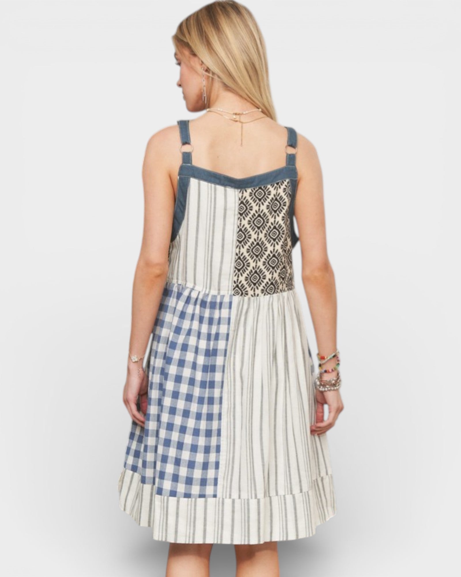 Woman wearing a dress with a patterned top and checkered skirt on a white background