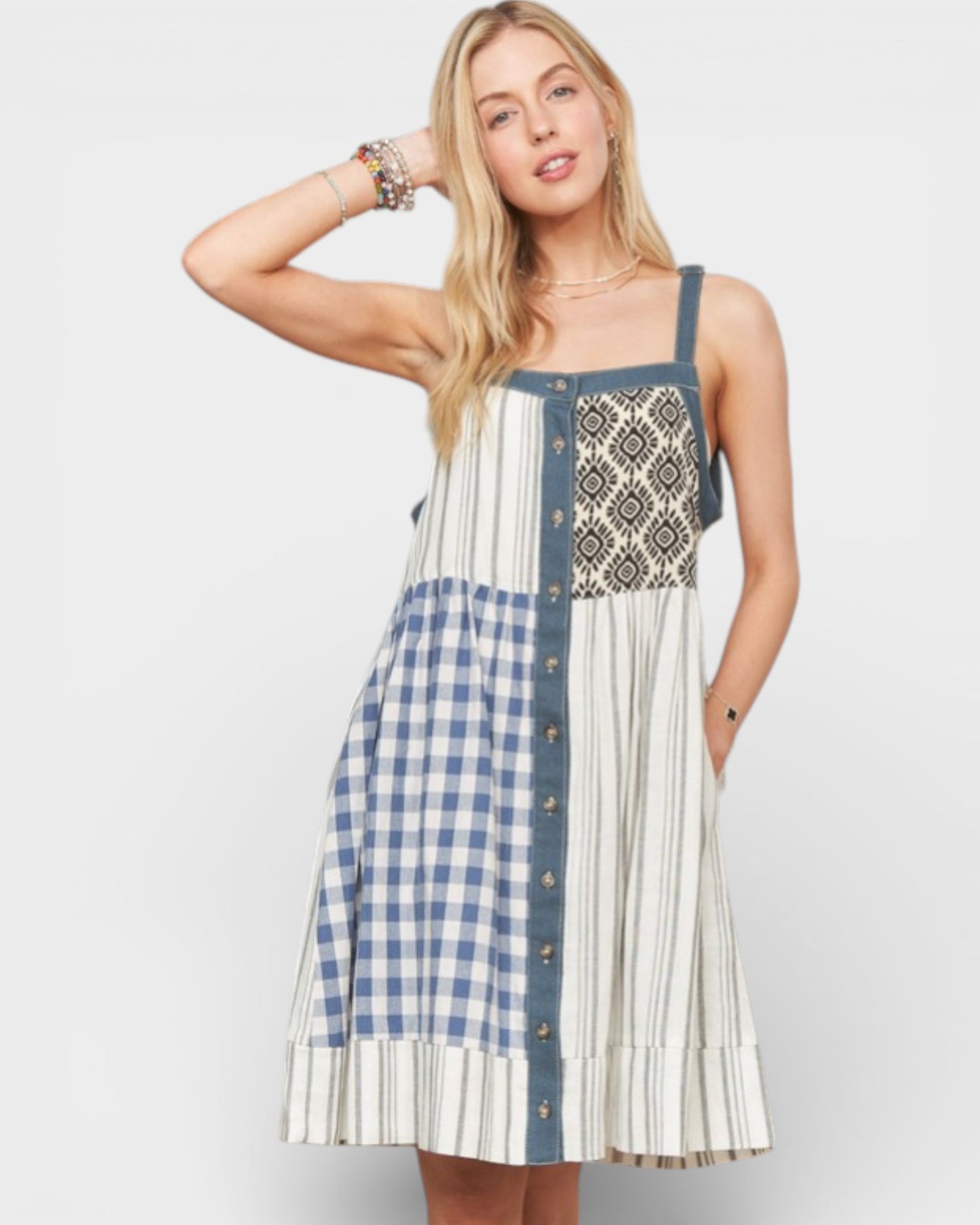 Woman wearing a patterned dress with a mix of checkered and striped designs on a plain background