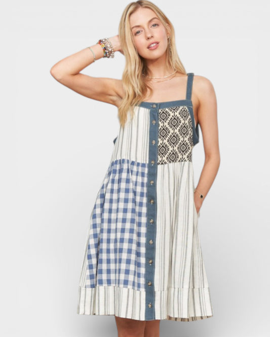 Woman wearing a patterned dress with a mix of checkered and striped designs on a plain background