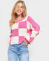 Woman wearing a pink and white checkered sweater with blue jeans on a light gray background
