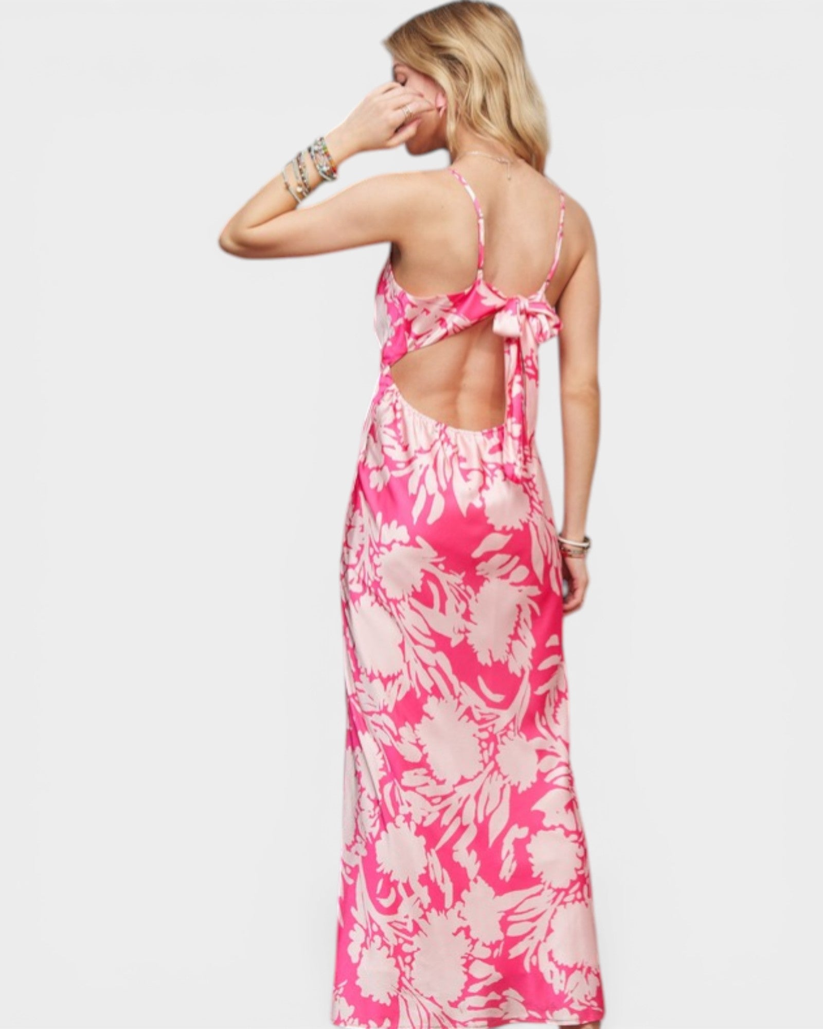 Woman wearing a pink floral dress with cut-out back on a white background