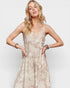 Woman wearing a beige floral dress against a plain background