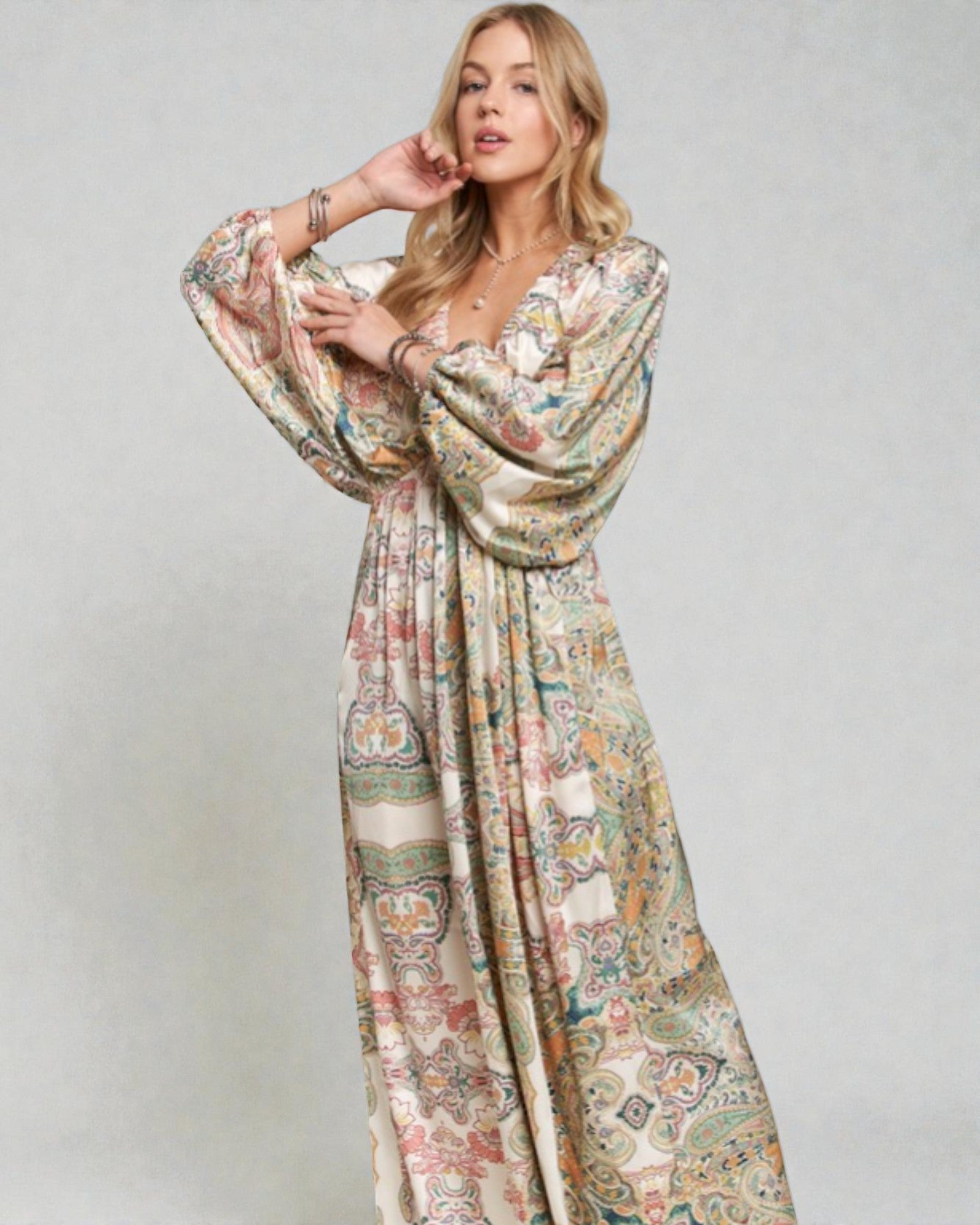 Woman wearing a long, patterned dress against a plain background