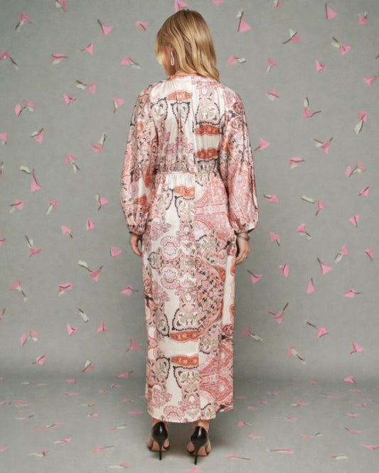 Woman wearing a long, patterned dress against a gray background with decorative elements.