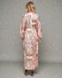 Woman wearing a long, patterned dress against a gray background with decorative elements.
