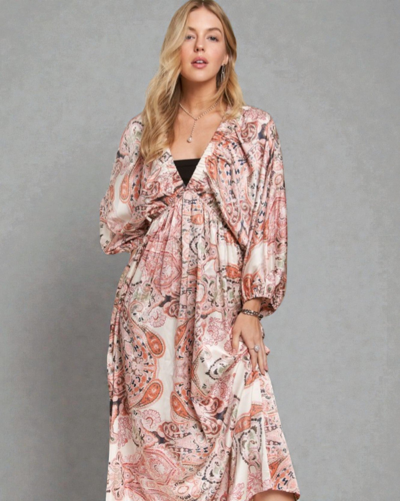 Woman wearing a long, patterned dress against a gray background