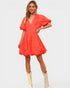 Woman wearing a bright orange dress with ruffled sleeves on a white background