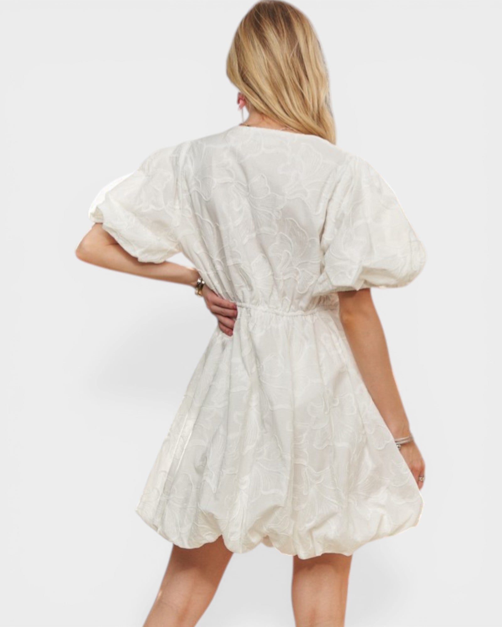 Woman wearing a white dress with puff sleeves on a plain background