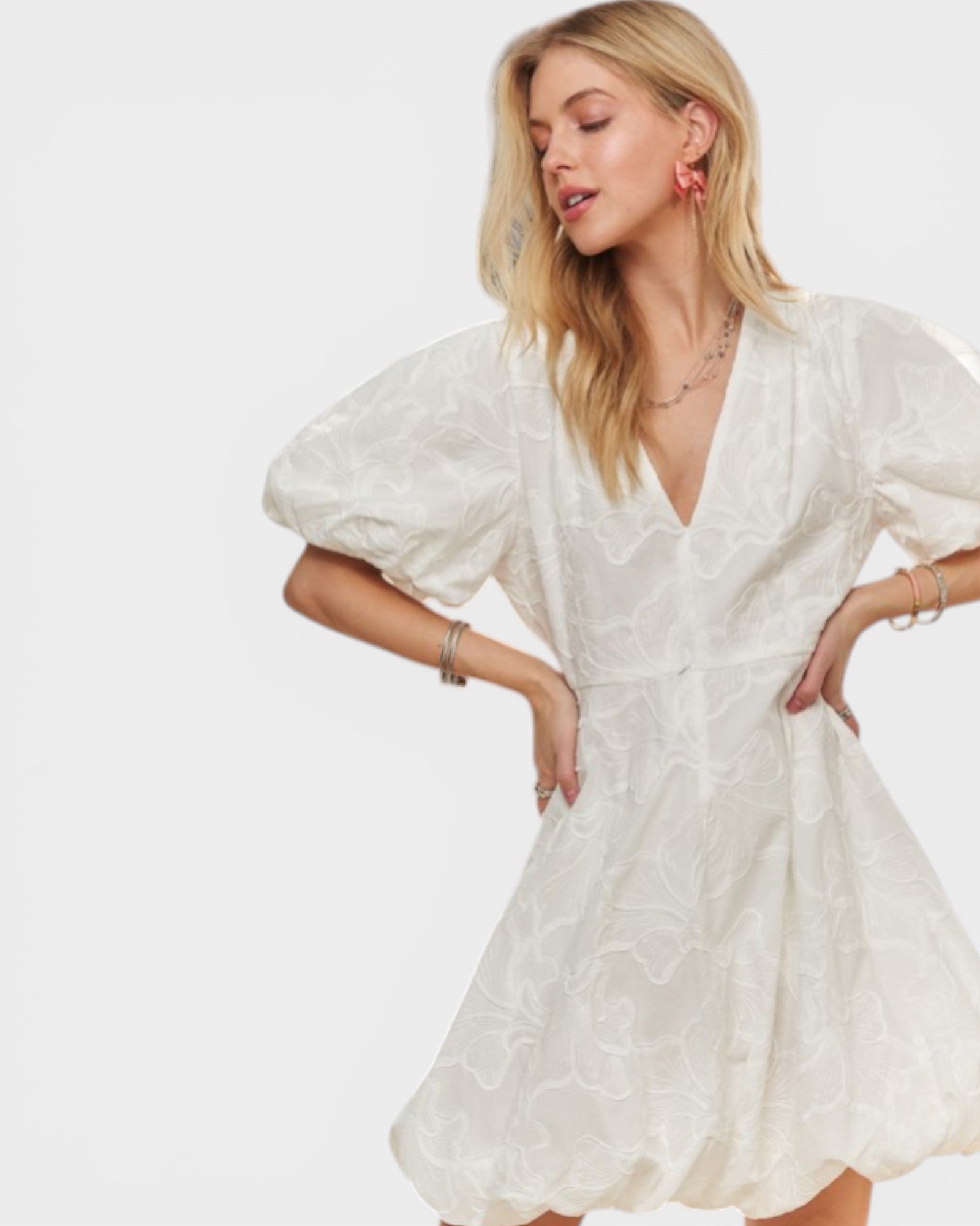 Woman wearing a white dress with puff sleeves on a plain background