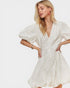Woman wearing a white dress with puff sleeves on a plain background
