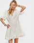 Woman wearing a white lace dress on a plain background