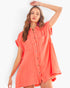 A woman modeling a short-sleeve, button-front shirt dress in a bright coral-orange color against a clean white background.