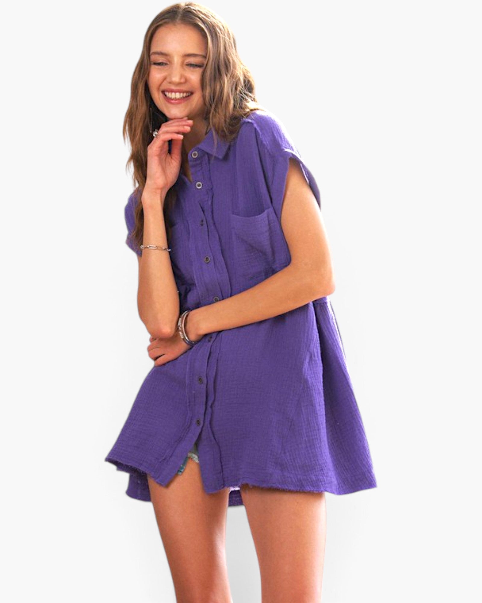 A woman modeling a purple sleeveless button-up shirt dress with a relaxed, oversized fit and a small chest pocket, set against a plain white background.