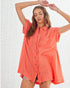 Woman wearing a coral oversized shirt against a white background