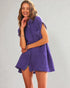 Woman wearing a purple sleeveless dress against a plain background