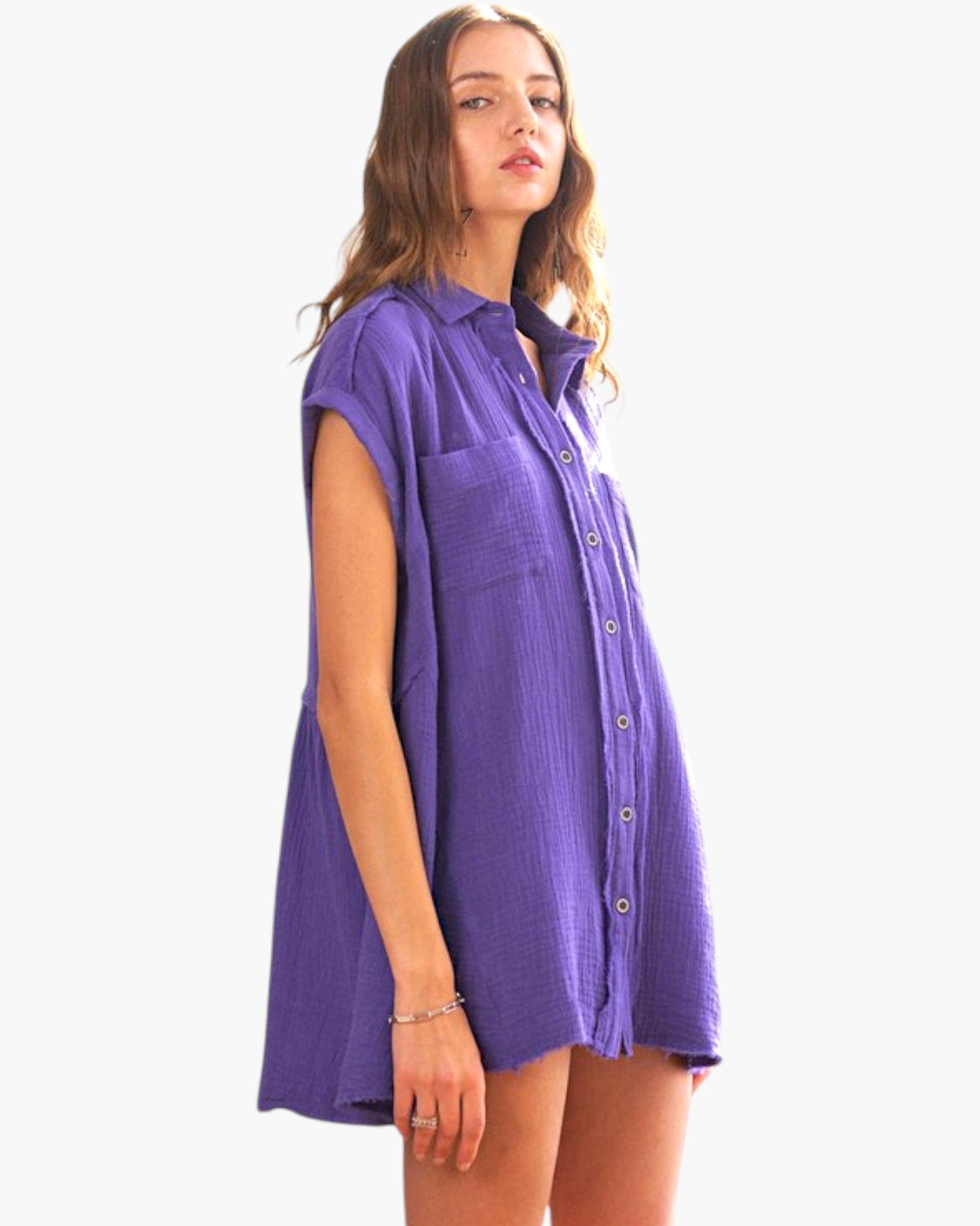 A woman modeling a purple short-sleeve button-down shirt dress against a plain white background.