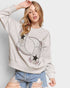 Woman wearing a light gray sweatshirt with a moon and star design on a plain background
