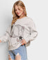 Woman wearing a gray sweatshirt with cowboy boot design on a plain background