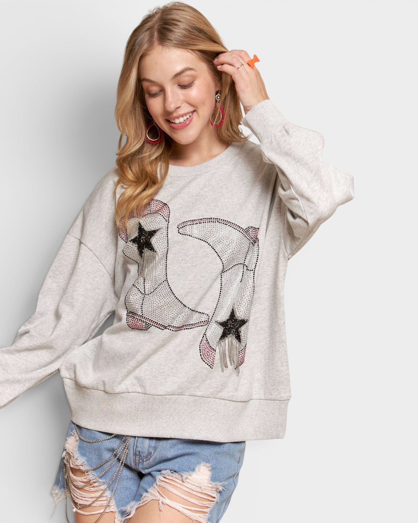 Woman wearing a light gray sweatshirt with a star and airplane design on a white background