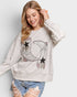 Woman wearing a light gray sweatshirt with a star and airplane design on a white background