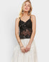 Woman wearing a black sequin top and white skirt on a light gray background