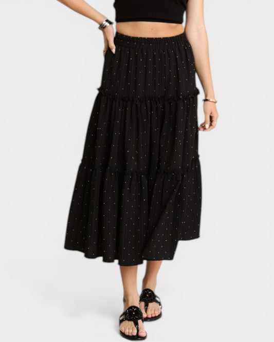 Person wearing a black tiered skirt with white polka dots on a white background