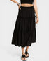 Person wearing a black tiered skirt with white polka dots on a white background