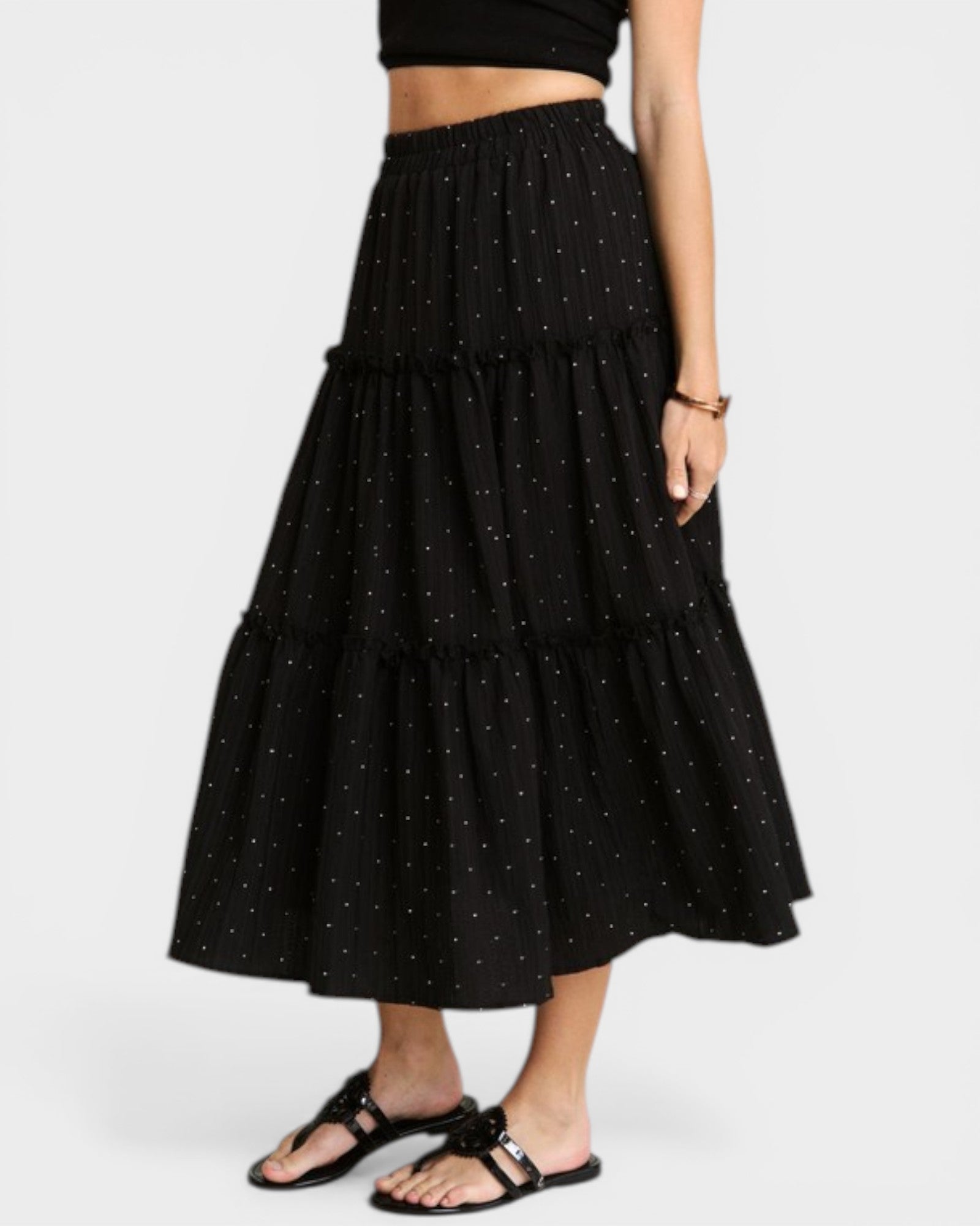 Black tiered skirt with white polka dots worn by a person on a white background