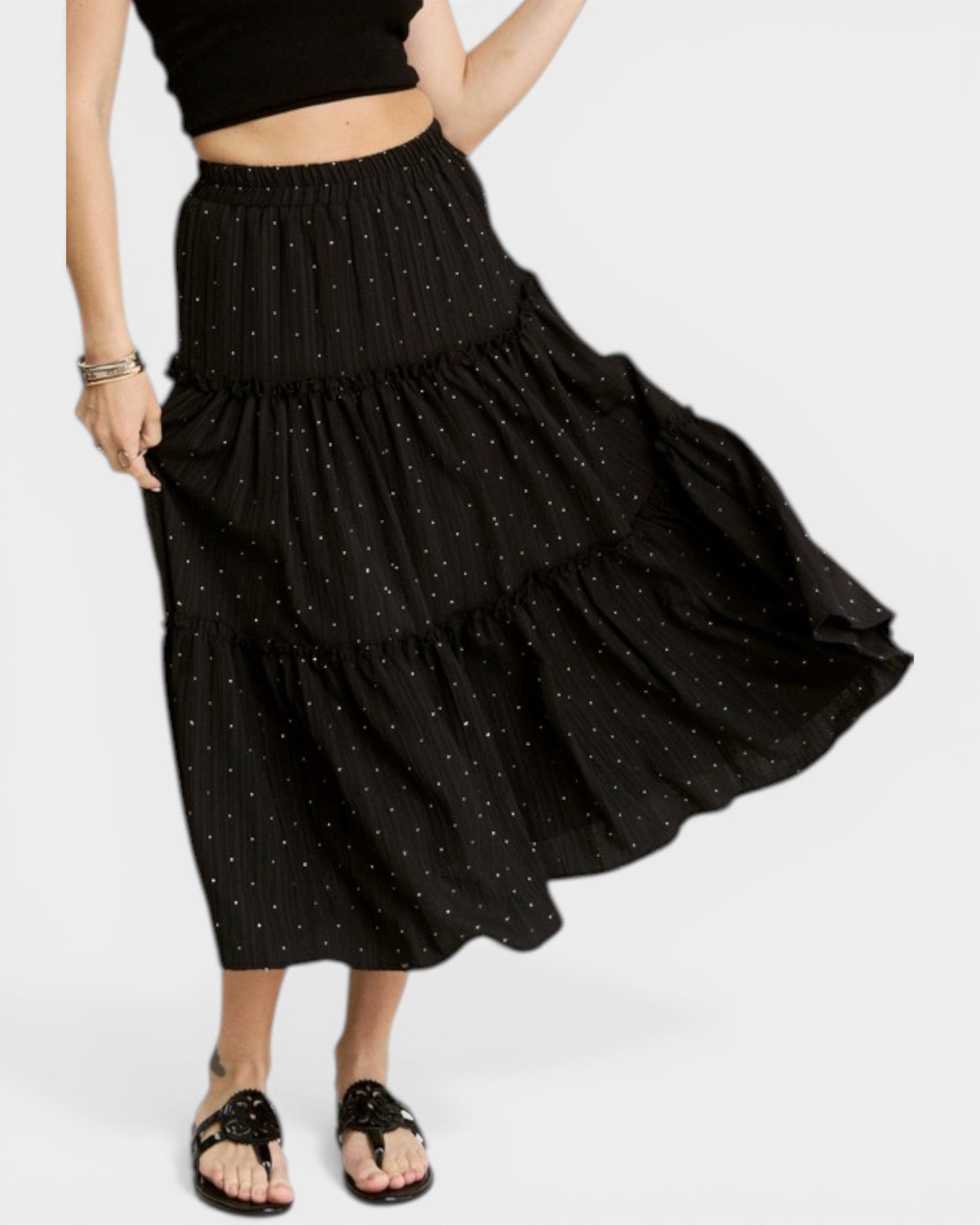 Black tiered skirt with white polka dots worn by a person on a white background