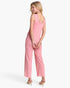 A woman modeling a pink sleeveless jumpsuit with wide legs, shown from a three-quarters back angle against a clean white background.