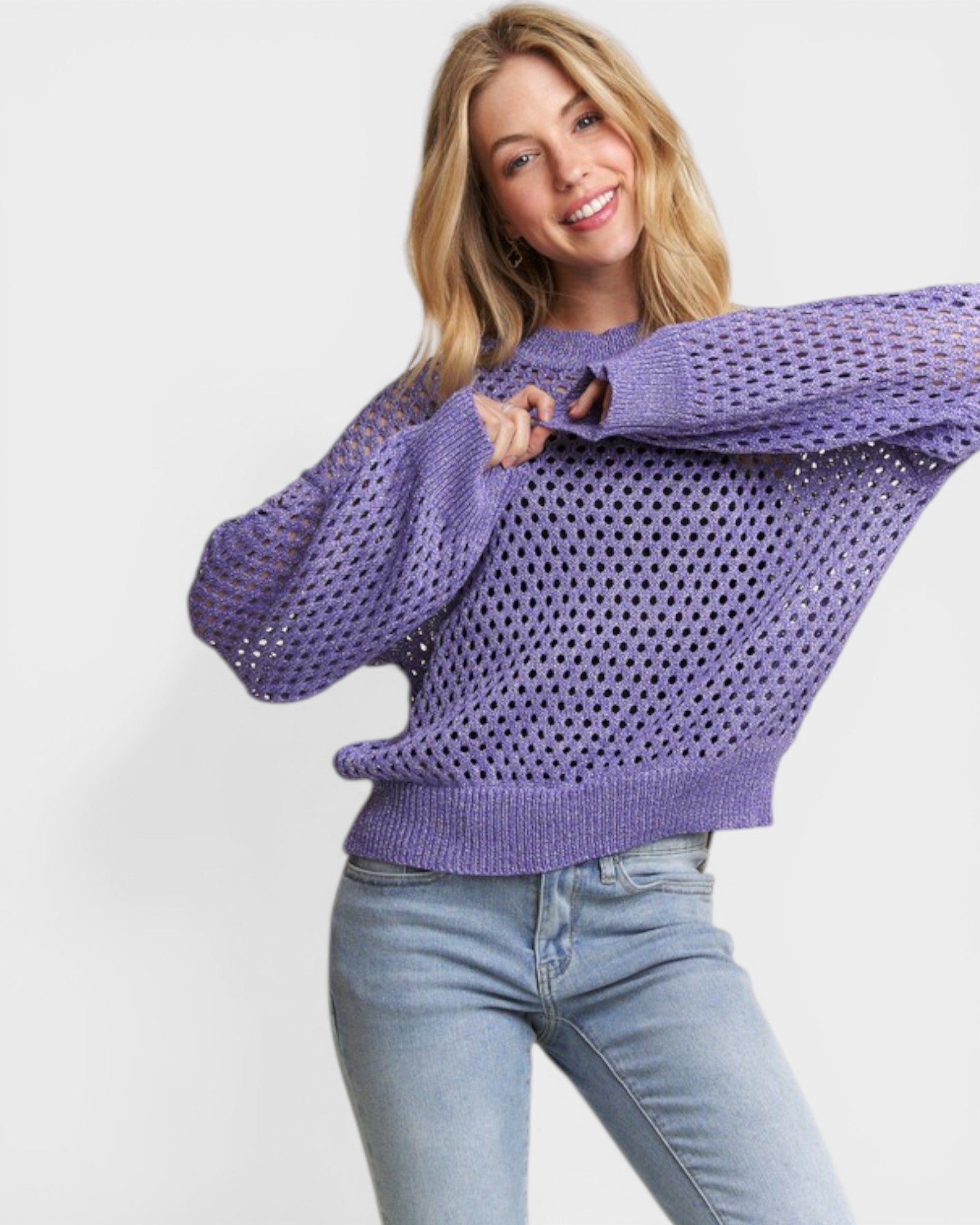 Woman wearing a purple sweater and light blue jeans on a white background