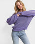 Woman wearing a purple sweater and light blue jeans on a white background