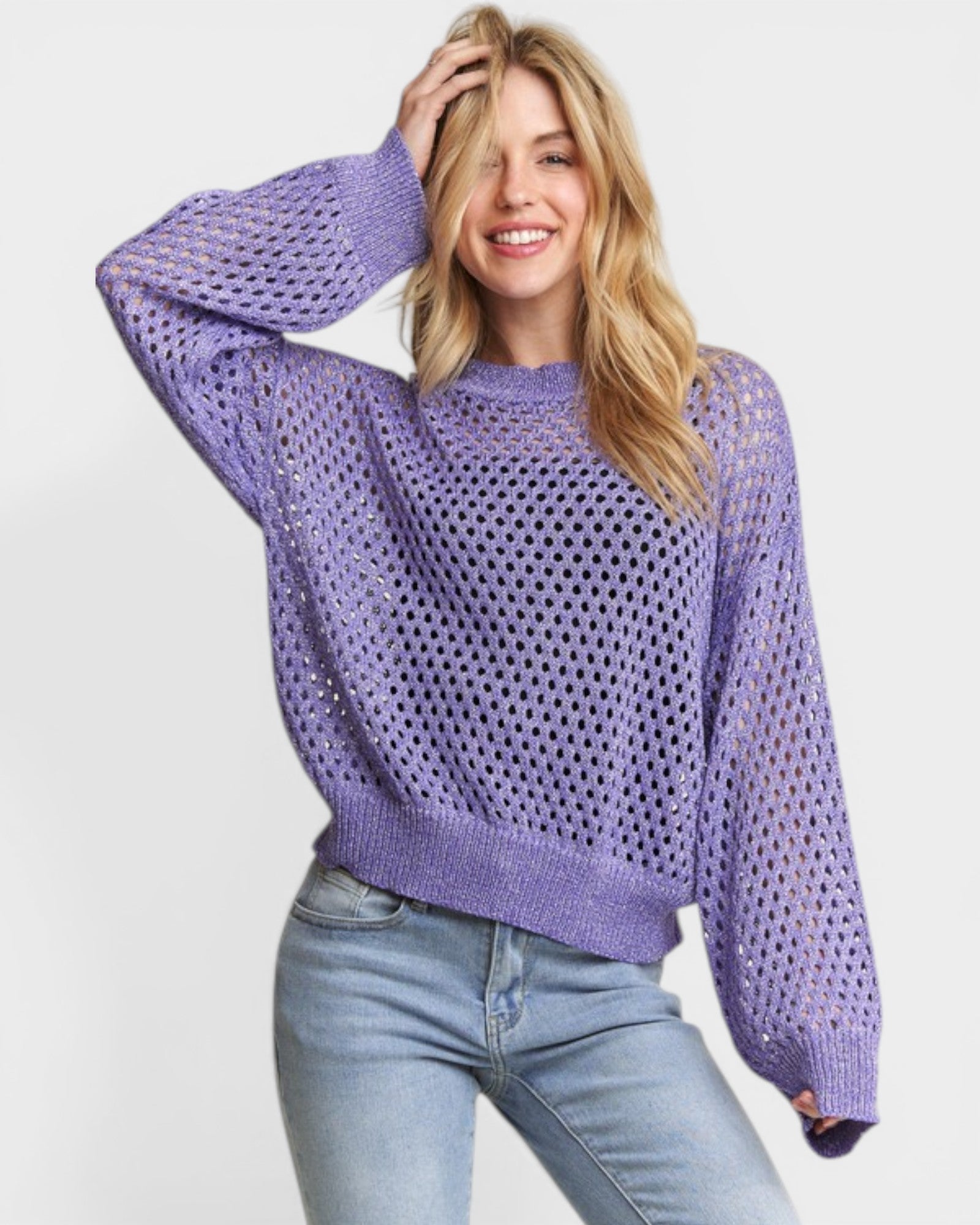 Woman wearing a purple open-knit sweater and light blue jeans on a white background