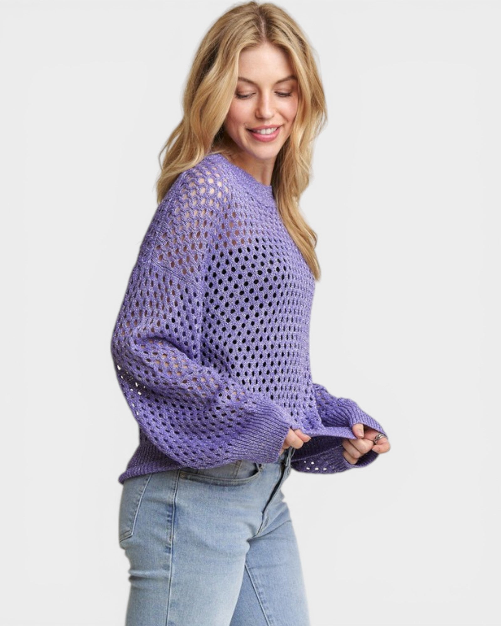 Woman wearing a purple open-knit sweater on a light gray background