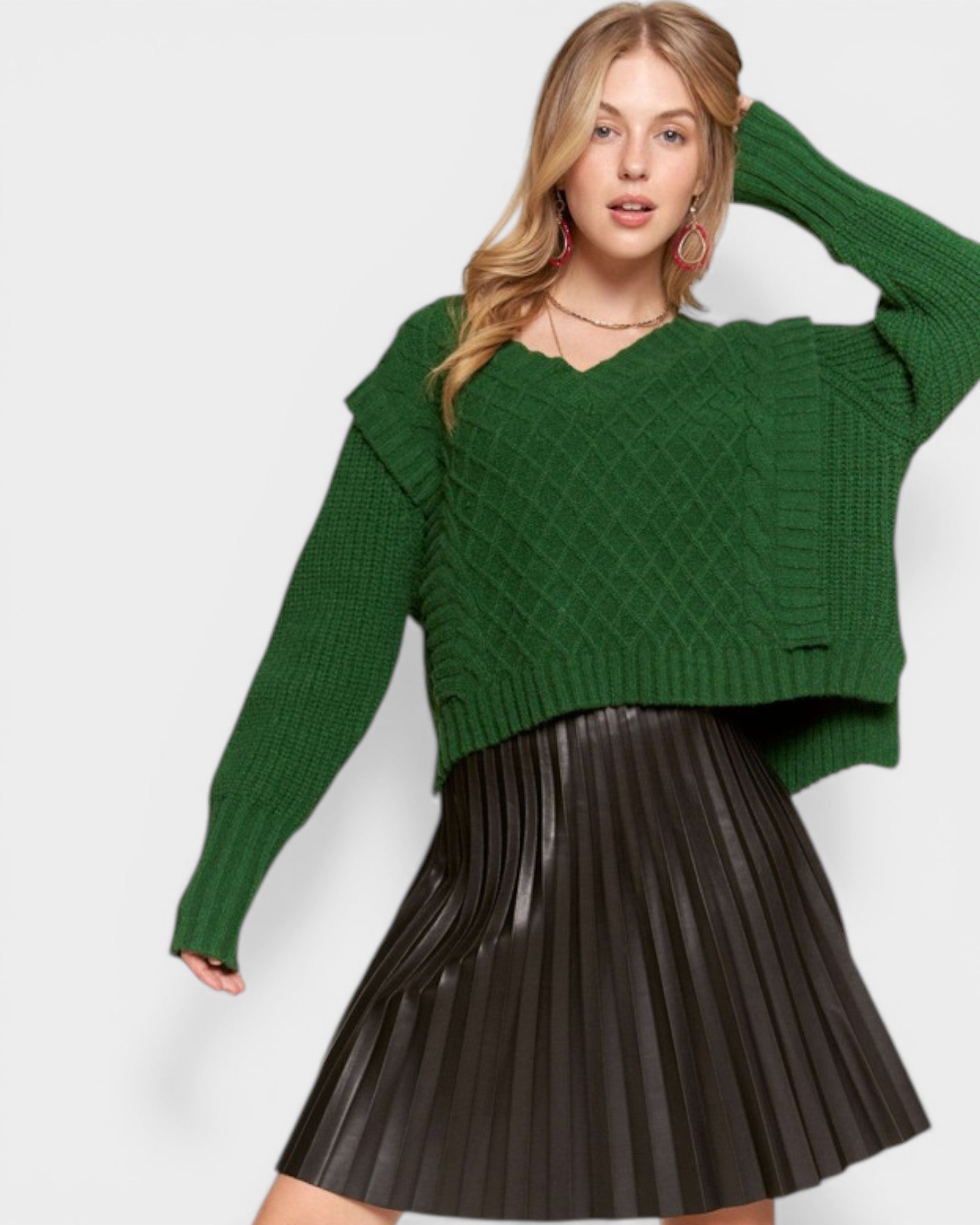 Woman wearing a green sweater and black pleated skirt on a white background