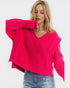 Woman wearing a bright pink sweater and blue jeans on a white background